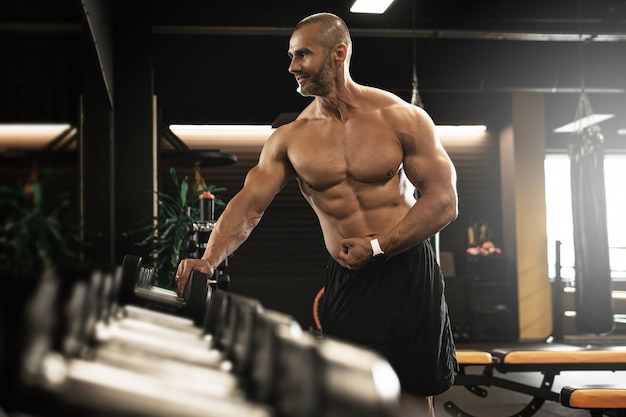 Entrenamiento de musculación y fitness. Culturista muscular en una zona de pesas en el gimnasio.