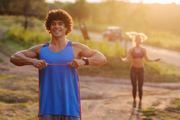 Entrenamiento en la naturaleza en un día soleado de verano. Feliz pareja deportiva enfocada entrenamiento juntos.