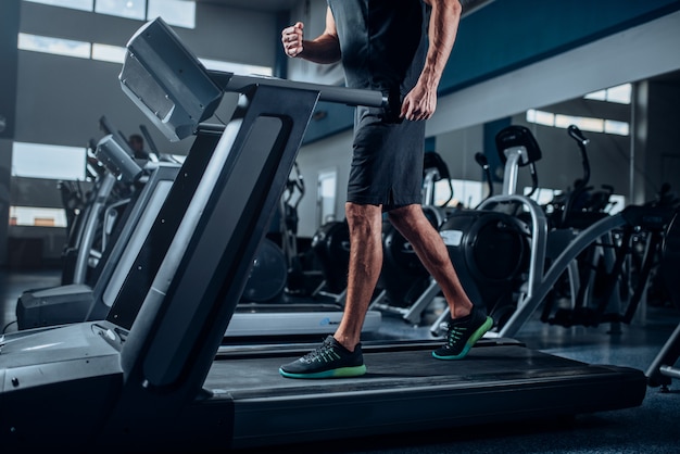 Entrenamiento de persona masculina en correr máquina de ejercicio