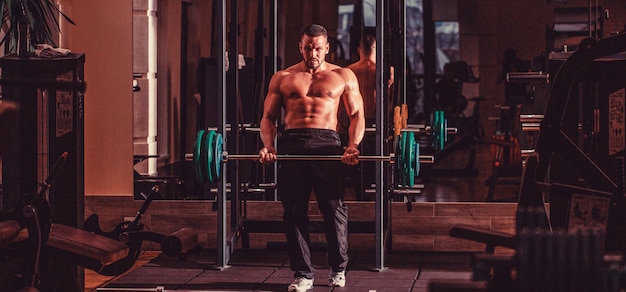 Entrenamiento con pesas Hombre atlético culturista con seis abdominales perfectos hombros bíceps tríceps pecho Hombre atlético de pie con entrenamiento con pesas en el gimnasio Entrenamiento de hombre musculoso con pesas en el gimnasio