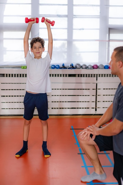 Entrenamiento con pesas con mancuernas para niños fortaleciendo brazos y hombros