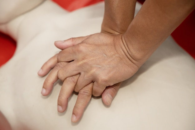Entrenamiento en primeros auxilios con RCP con la mano sobre el maniquí de cuerpo entero