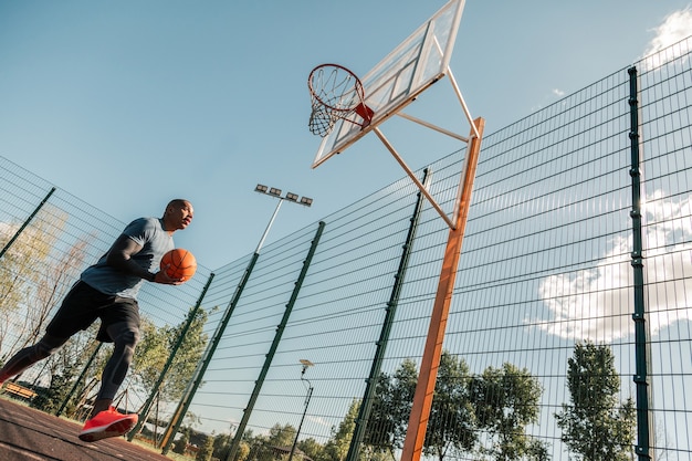 Entrenamiento profesional. Apuesto hombre afroamericano sosteniendo una pelota mientras tiene un entrenamiento