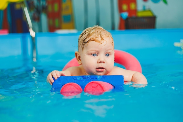 Entrenamiento de un recién nacido en una piscina Una piscina para bebés Desarrollo infantil Un niño pequeño aprende a nadar en la piscina