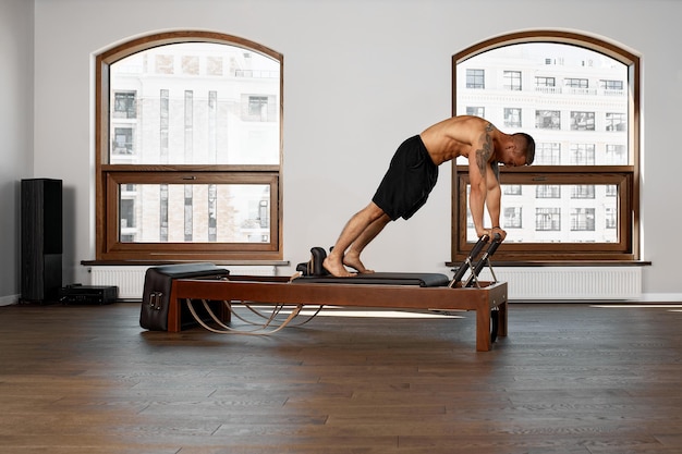 El entrenamiento del reformador de Pilates ejercita al hombre en el gimnasio interior.