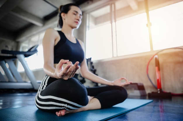Entrenamiento sano del cuerpo de la forma de vida asiática de la mujer joven en el gimnasio, concepto de la yoga del estilo de los deportes