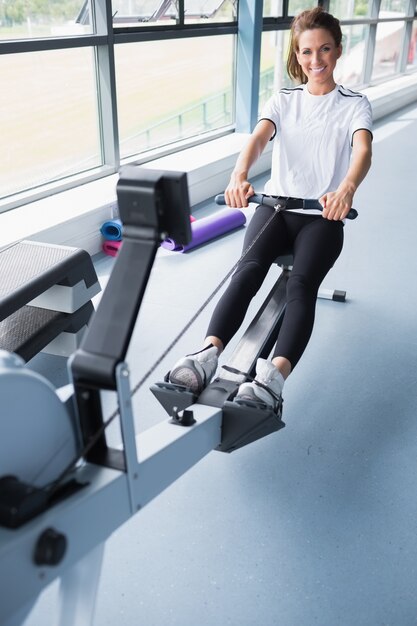 Entrenamiento sonriente de la mujer en la máquina de la fila