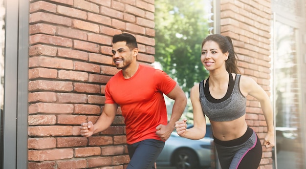 Entrenamiento temprano en la mañana. Pareja activa corriendo todos los días al aire libre, panorama, espacio de copia