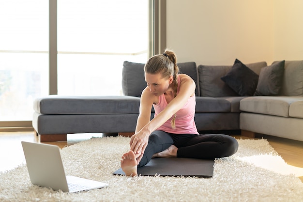 Entrenamiento de yoga en línea deporte fitness. mujer joven y haciendo ejercicios en estera de yoga