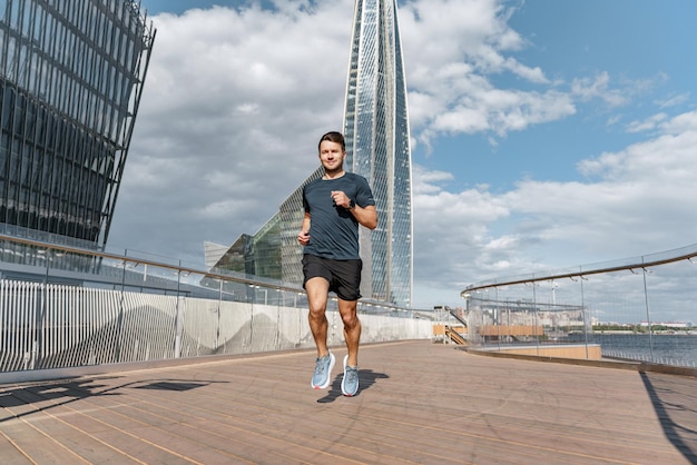 Entrenando en zapatillas de correr de longitud completa Un corredor es un hombre joven con ropa deportiva cómoda