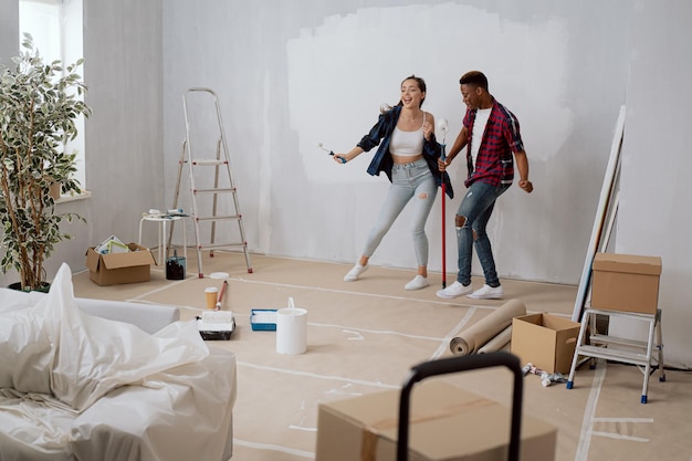 Foto entretenidos amigos alegres pasan tiempo juntos y se divierten mientras renuevan el apartamento de la habitación