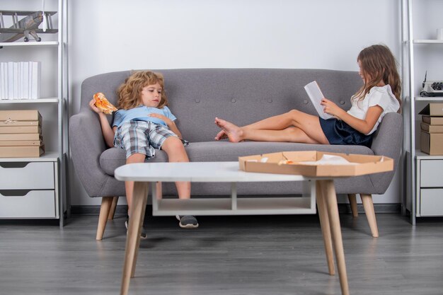 Entretenimento de lazer para crianças em casa para crianças bonitas comendo pizza lendo livro desfrutando de lazer em