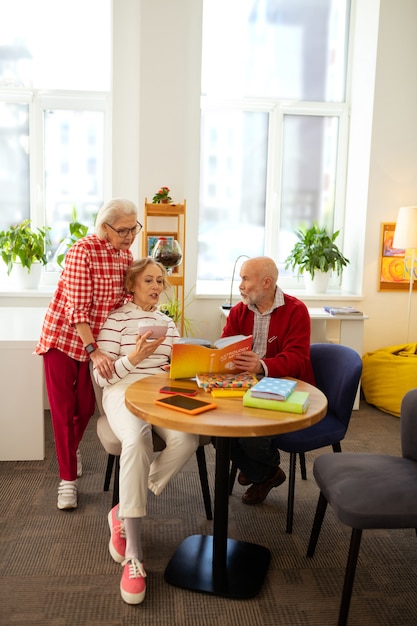 Entretenimiento agradable. Agradables personas mayores hablando de libros mientras disfrutan de su tiempo juntos