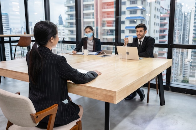 Foto entrevista de emprego de um empregador de recursos humanos caucasiano com a secretária e uma jovem candidata asiática em um escritório moderno