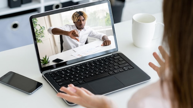 Foto entrevista en video desacuerdo en línea negociación virtual hombre de negocios insatisfecho en la pantalla de una computadora portátil que rechaza la oferta con un gesto con el pulgar hacia abajo a una pareja sorprendida encogiéndose de hombros