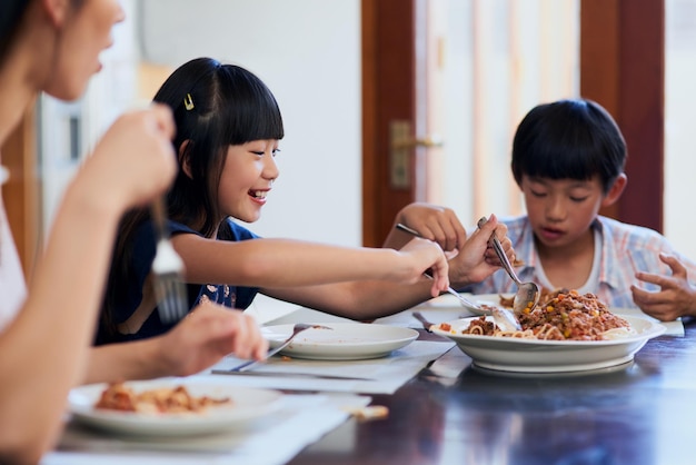 Entro por unos segundos Fotografía de dos niños pequeños disfrutando de una comida con su madre en casa