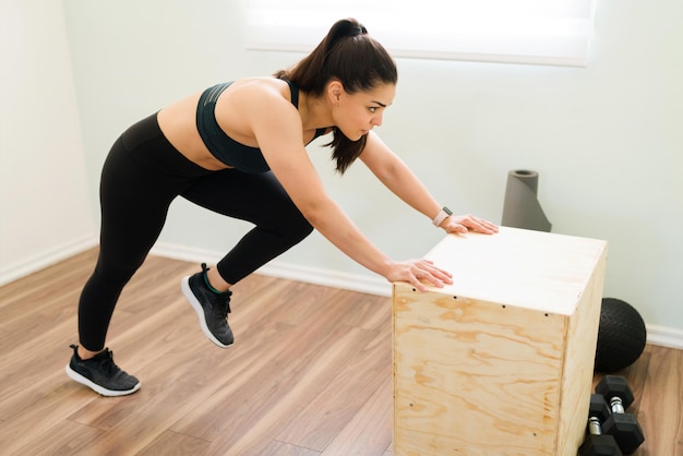 Entschlossene junge Frau, die zu Hause ein starkes Cardio-Training macht. Sportlerin trainiert mit Bergsteigern mit Sprungbox