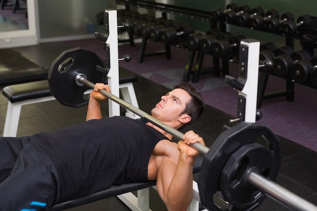 Entschlossener muskulöser Mann, der Barbell anhebt