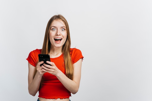 Foto entsetzte frau, die ihr telefon mit kopienraum hält