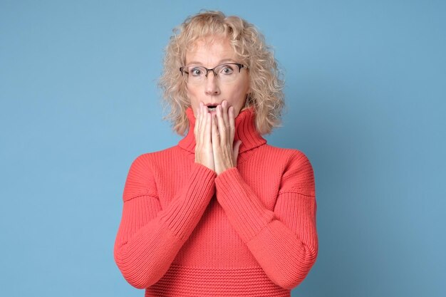 Foto entsetzte reife frau bedeckt ihren mund mit den händen