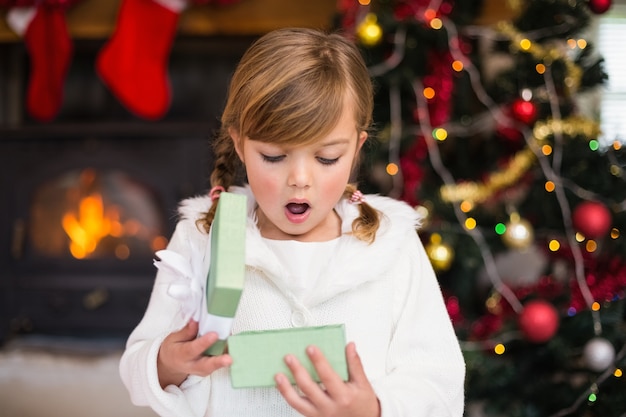 Entsetztes kleines Mädchen, das ein Geschenk öffnet