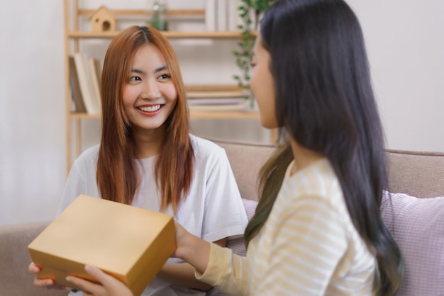 Entspannen Sie sich zu Hause Konzept LGBT-lesbische Frau lächelt, während sie eine Geschenkbox von der Freundin erhält