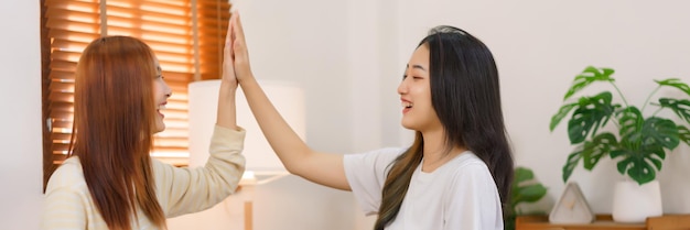 Entspannen Sie sich zu Hause Konzept LGBT-lesbisches Paar, das zusammen High Five gibt, während es im Wohnzimmer sitzt