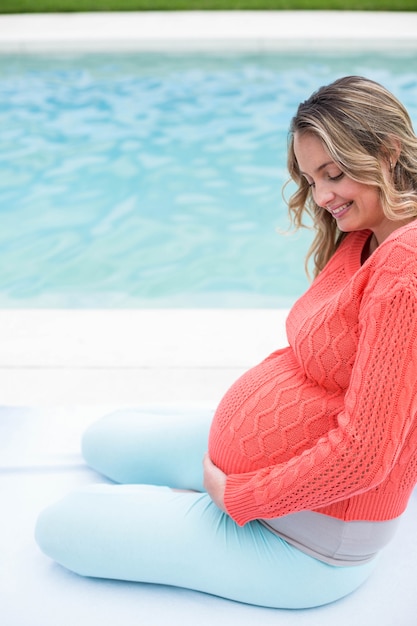 Entspannende Außenseite der schwangeren Frau nahe bei dem Pool