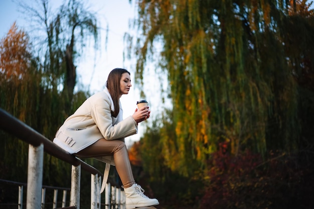 Entspannende Dame des hübschen Herbstlebensstils Schöne junge Frau mit Kaffee im Park