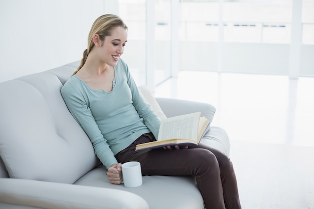 Entspannende Lesung der attraktiven Blondine ein Buch, das eine Schale anhält