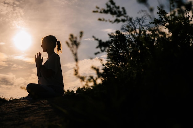 Entspannte Dame führt namaste Yoga-Pose-Hintergrund der Sonne im Freien auf Park außerhalb des Stadtabends durch