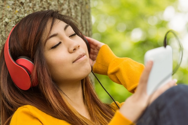 Entspannte Frau, die Musik im Park genießt