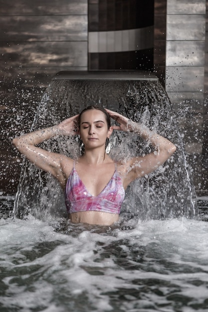 Entspannte Frau, die Spritzwasserstrom im Spa-Zentrum genießt