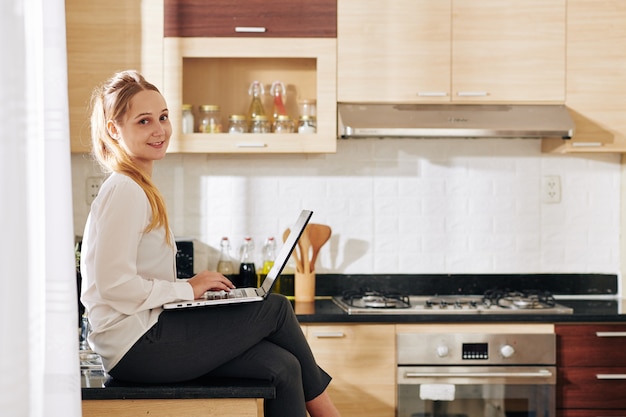 Entspannte Frau mit Laptop in der Küche