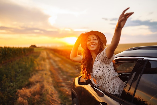 Entspannte, glückliche Frau auf einem Sommer-Roadtrip-Reiseurlaub, der sich aus dem Autofenster lehnt