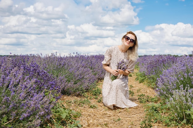 Entspannte junge Frau, die an einem sonnigen Tag auf einem Lavendelfeld sitzt