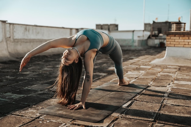 Entspannte junge Frau, die Yoga auf einer Dachterrasse praktiziert.