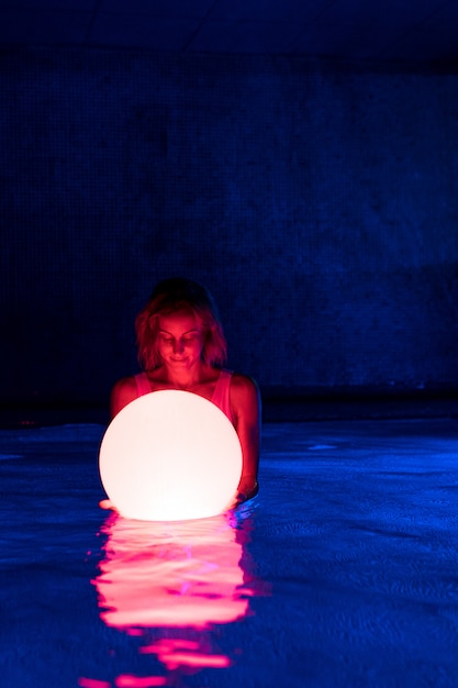 Entspannte junge Frau im Pool mit Neonlicht