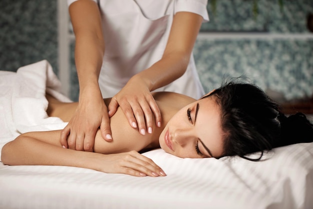 Entspannte schöne junge Frau, die Massage im Spa-Salon empfängt. Schönheitsbehandlung
