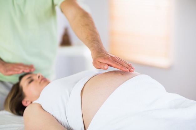 Entspannte schwangere Frau, die reiki Behandlung erhält