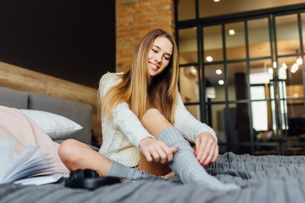 Entspannte verspielte Frau mit T-Shirt, Shorts und Socken, die einen faulen Morgen hat