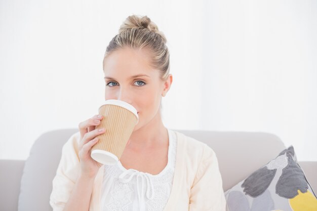 Entspannter frischer vorbildlicher trinkender Kaffee, der auf Sofa sitzt