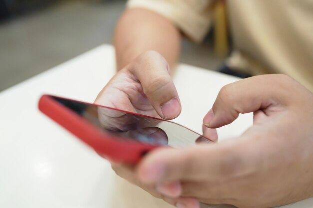 Entspannter junger asiatischer Mann benutzt Smartphone und verbringt Zeit damit, Nachrichten und soziale Medien zu checken