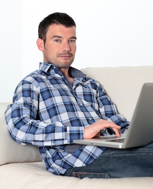 Entspannter Mann auf Sofa mit Computer