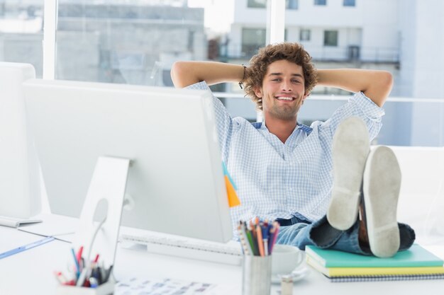 Foto entspannter zufälliger mann mit den beinen auf schreibtisch im hellen büro