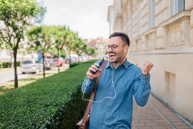 Entusiasmado jovem empresário adulto ouvindo música cantando e dançando lá fora