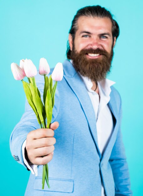 Entusiasmo hombre con barba y cabello elegante vacaciones y celebración regalo floral para madres o mujeres