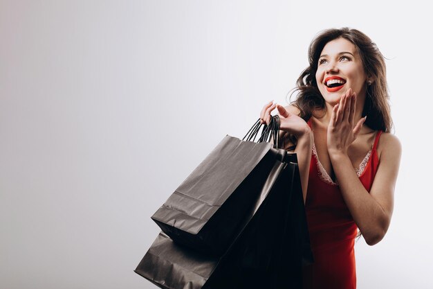 Entusiasta chica de compras elegante con bolsas de compras está gratamente sorprendida