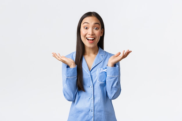 Entusiasta feliz hermosa niña asiática en pijama azul escuchar una gran idea, aplaudir y mirar asombrada, escuchando maravillosos consejos. Mujer divirtiéndose en la fiesta de pijamas con amigas en pijama.