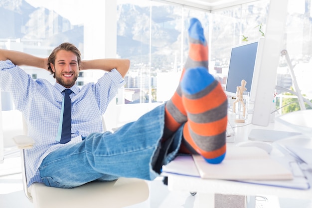 Entwerfer, der am Schreibtisch ohne Schuhe und Lächeln sich entspannt